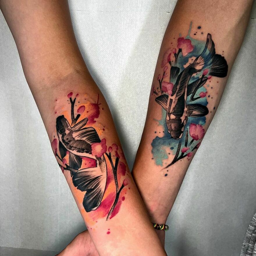 Two forearms with beautiful watercolor tattoos of koi fish and cherry blossoms.