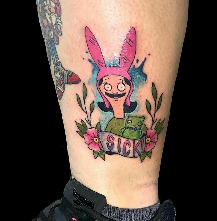 Cartoon tattoo of a character with pink bunny ears, vibrant design with flowers and "Sick" banner, childhood's favorites theme.