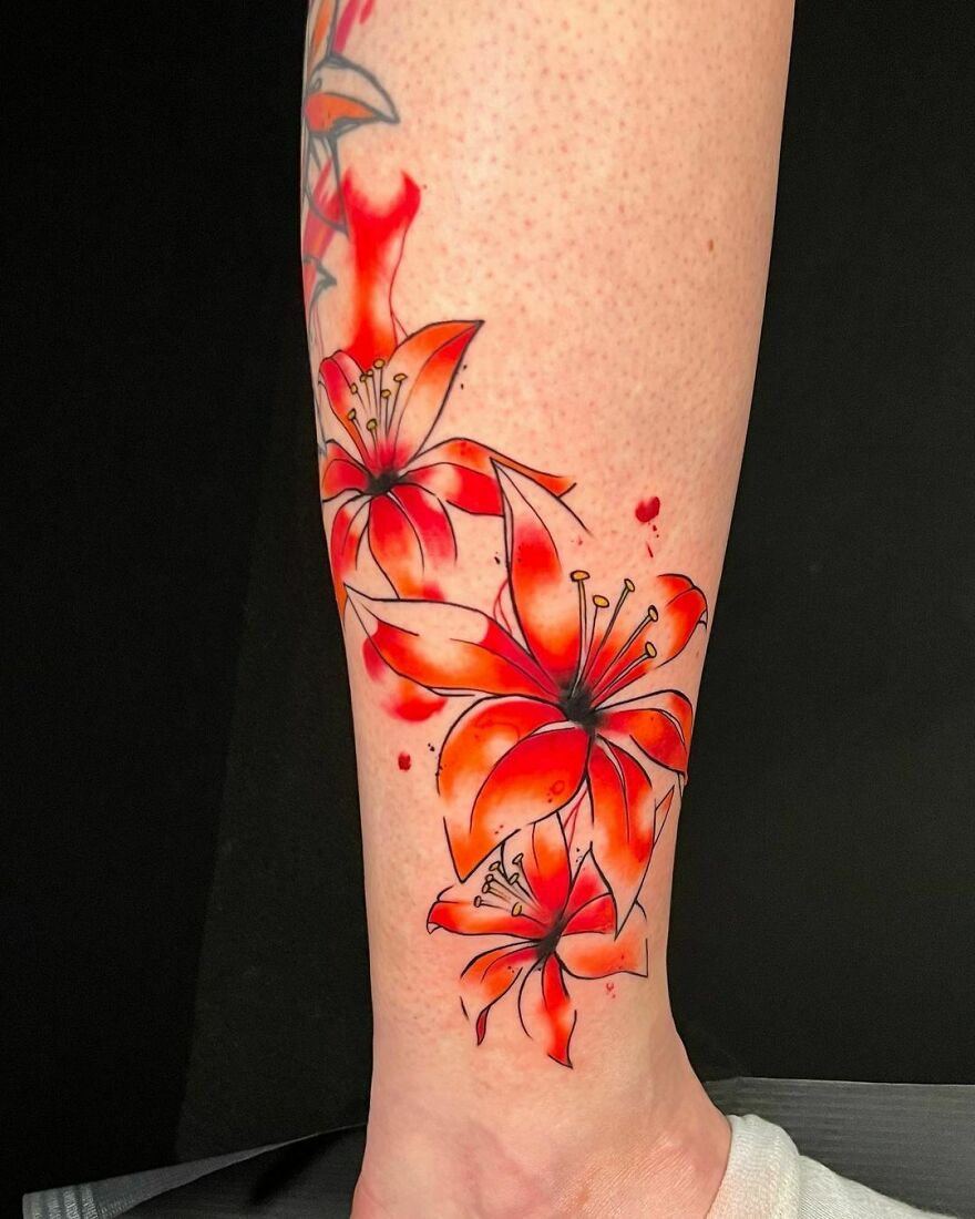 Beautiful watercolor tattoo of red lilies on forearm.