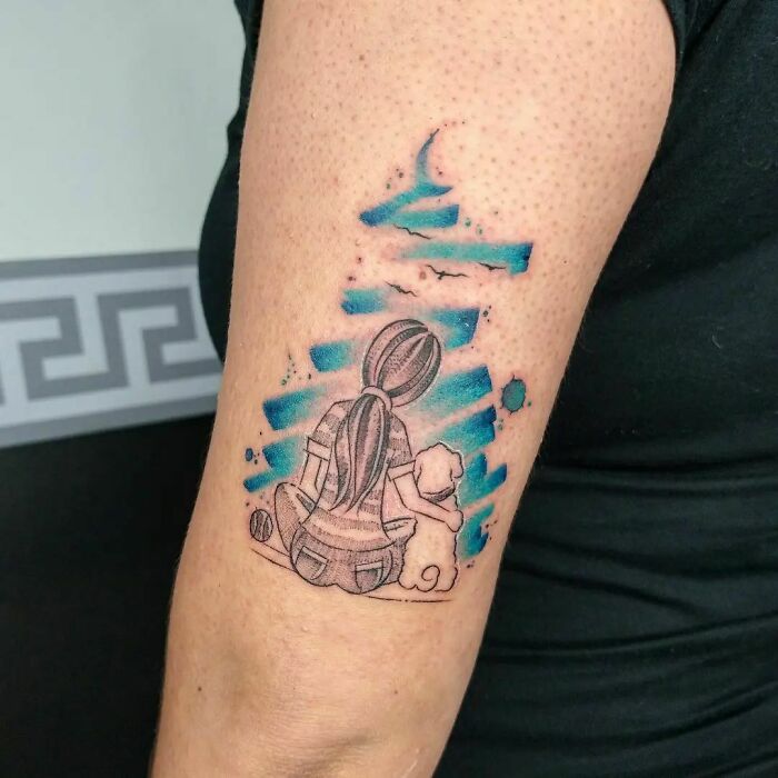 Watercolor tattoo of a girl with a dog, blue sky elements, and a crescent moon on an arm.