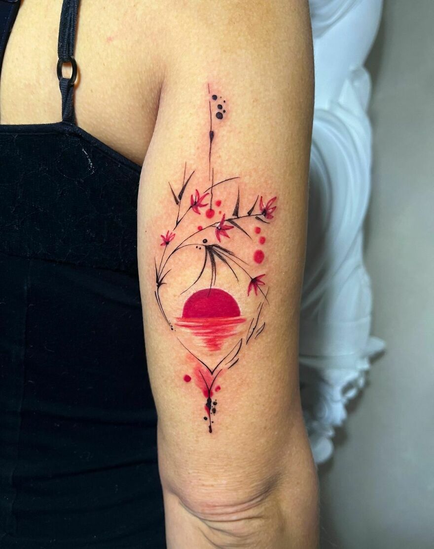 Watercolor tattoo on arm featuring a red sun with delicate floral designs.
