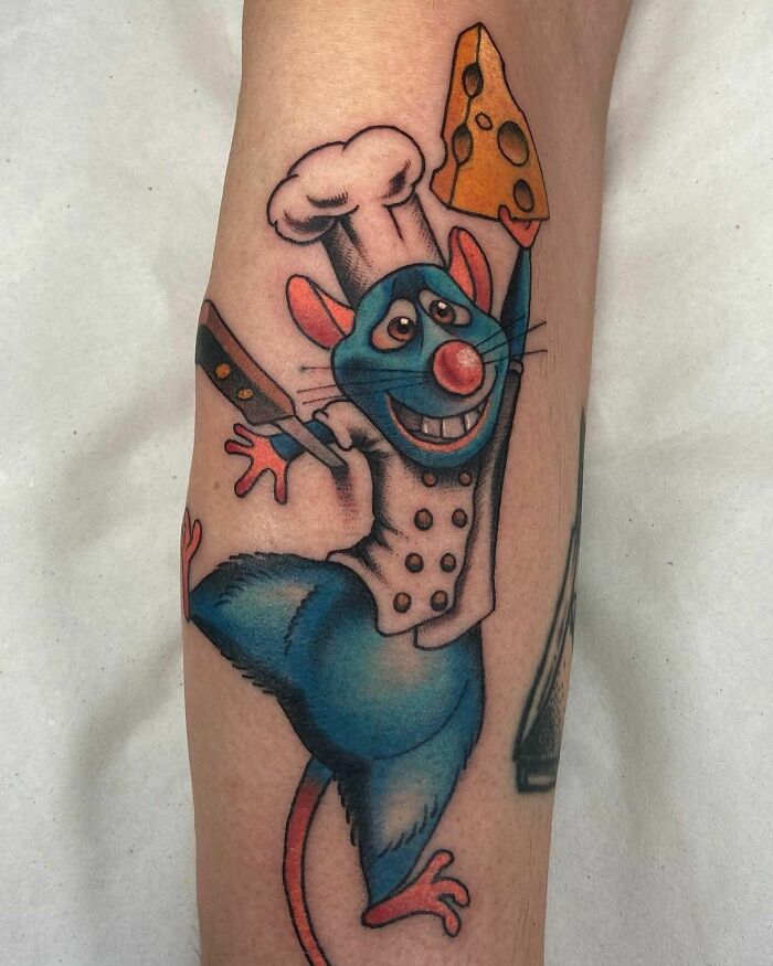 Cartoon tattoo of a chef rat holding cheese, inspired by animated shows.