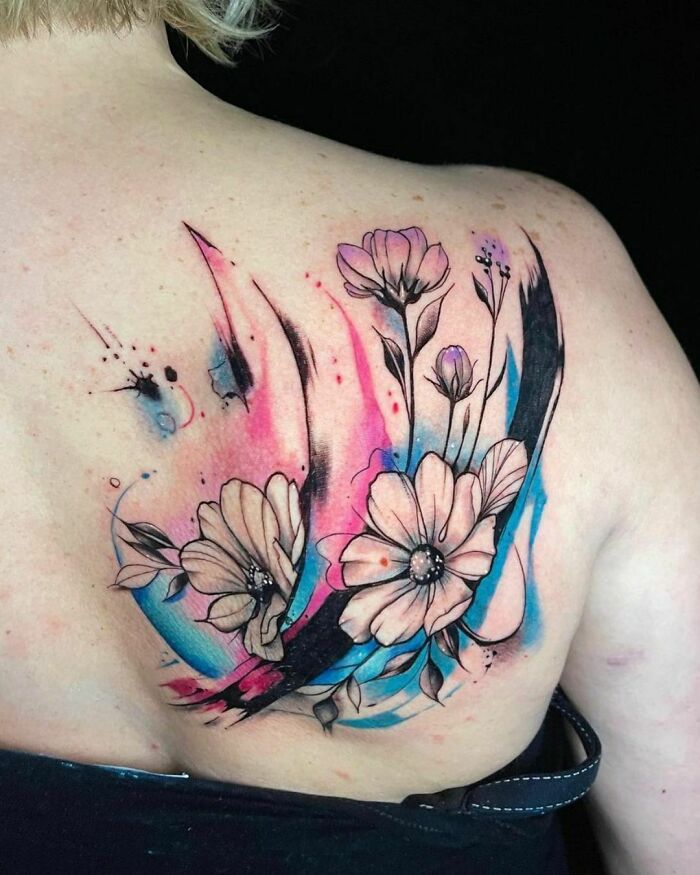 Watercolor tattoo of flowers with pink and blue accents on shoulder, showcasing beautiful inkspiration.