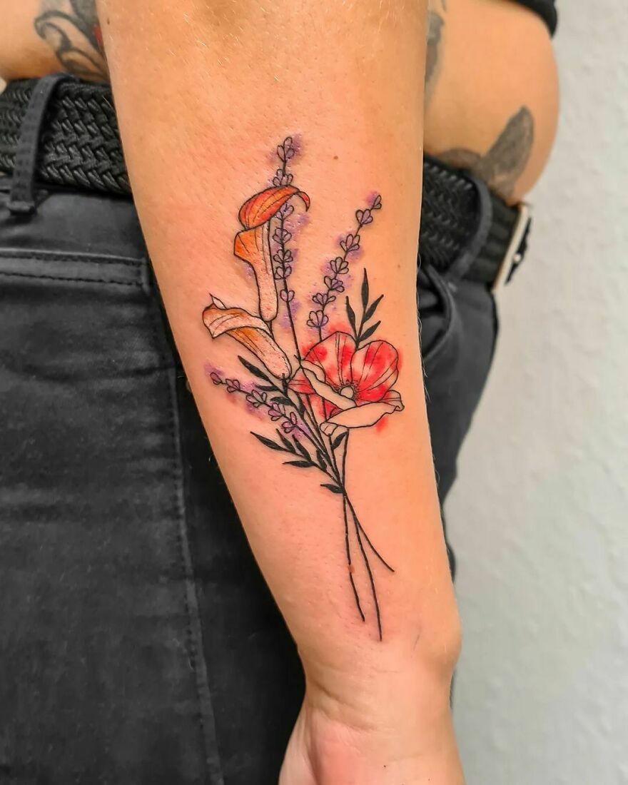 Watercolor tattoo of red and orange flowers with green stems on a forearm.