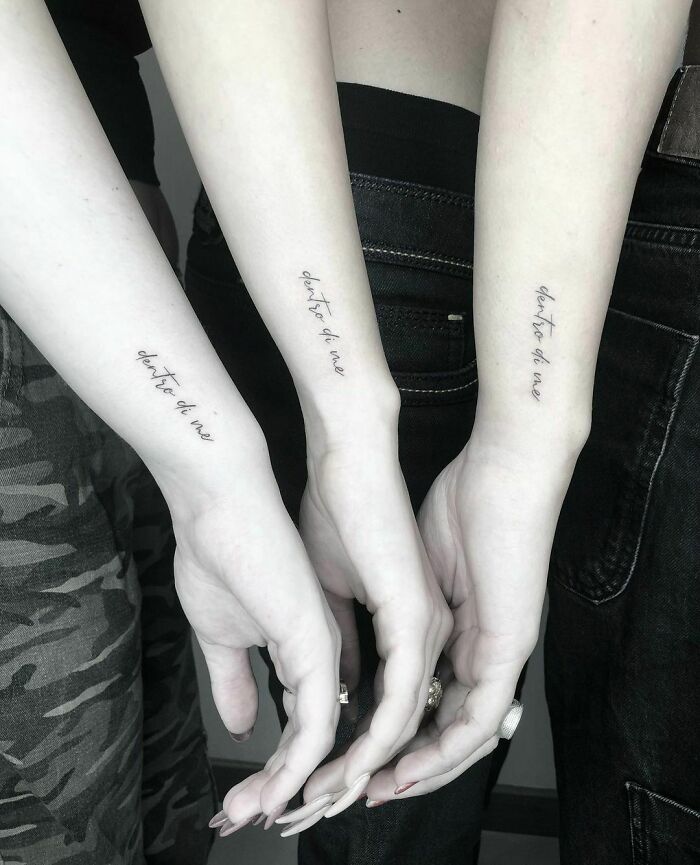 Three arms with word tattoos in cursive script, highlighting personal expressions through ink designs.