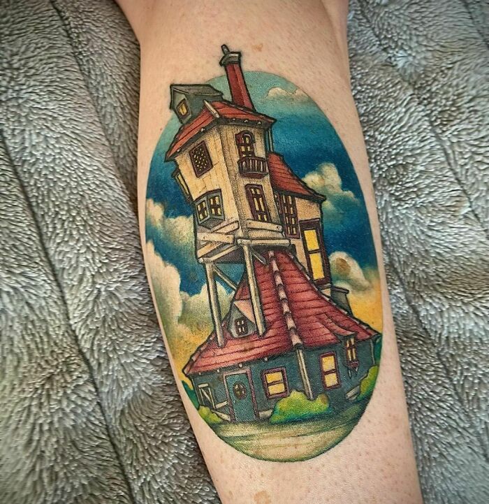 Harry Potter tattoo depicting the iconic Weasley family house, the Burrow, with vibrant colors on a forearm.