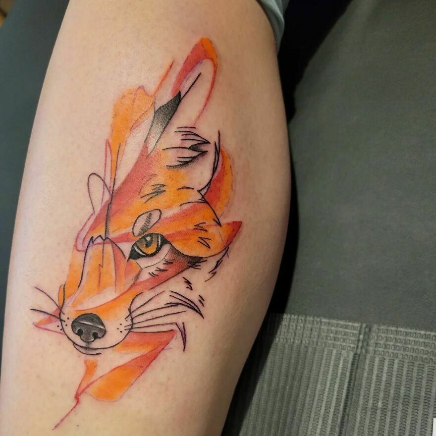 Watercolor tattoo of an abstract fox design on a person's forearm.