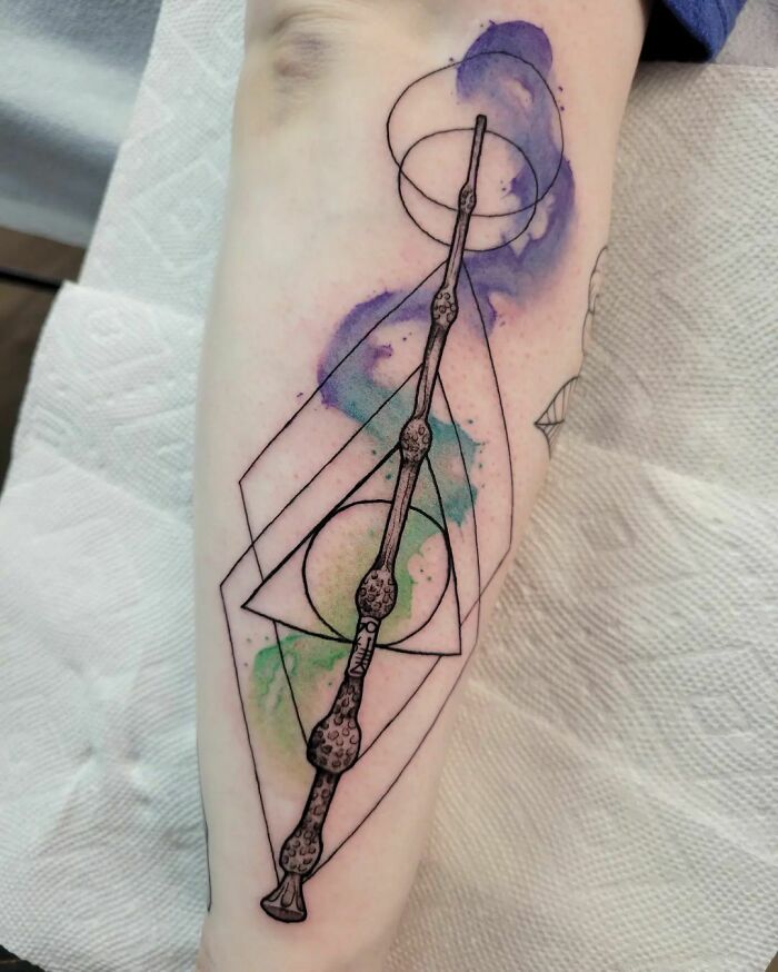 Geometric watercolor tattoo with abstract design on forearm.