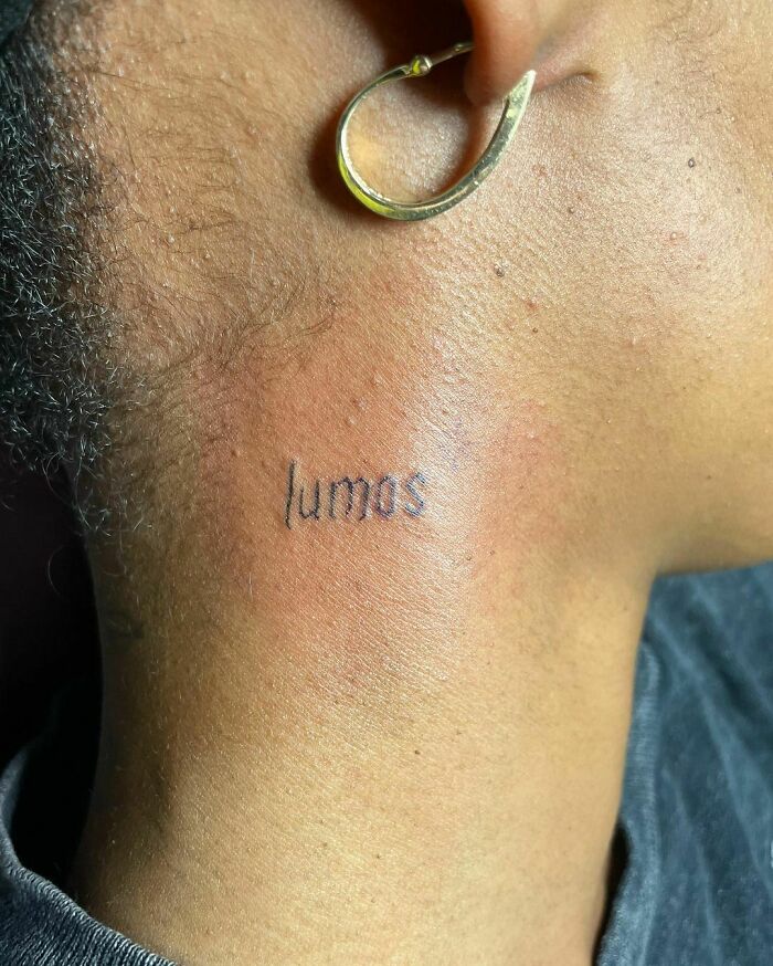 "Lumos Harry Potter tattoo on neck next to an earring, showcasing magical design inspiration for fans."