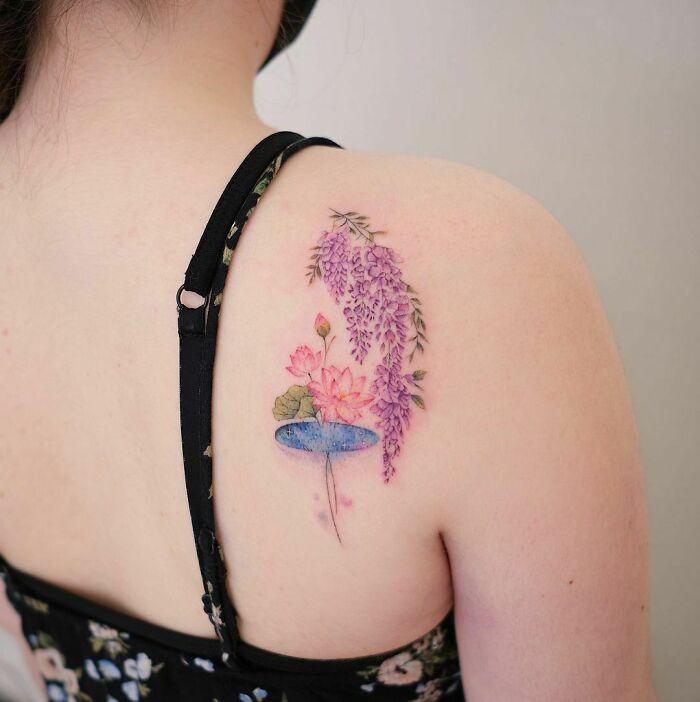 Watercolor tattoo of pink flowers and wisteria on shoulder, showcasing ethereal art.