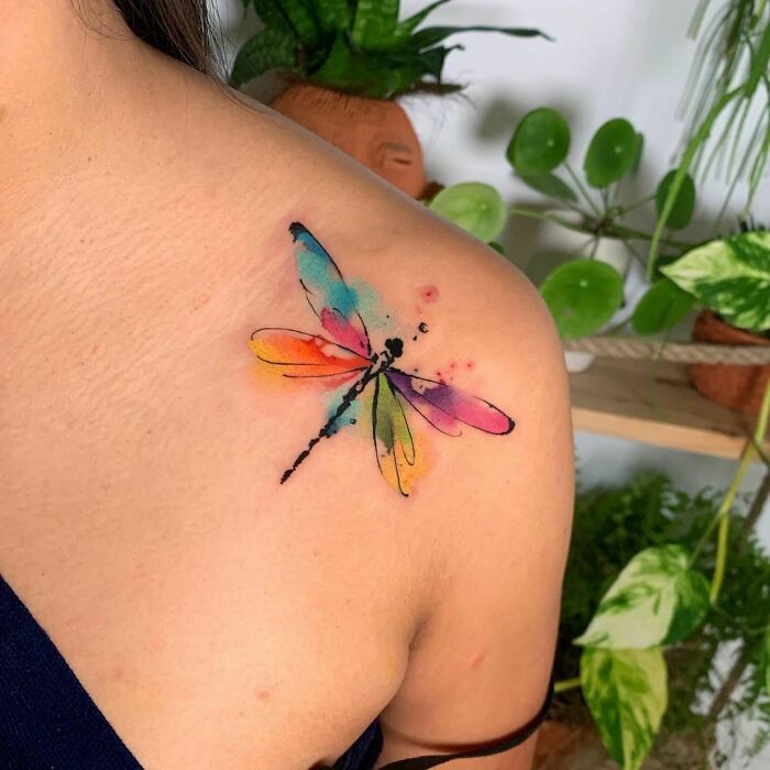 Colorful watercolor tattoo of a dragonfly on a shoulder, showcasing artistic inkspiration.