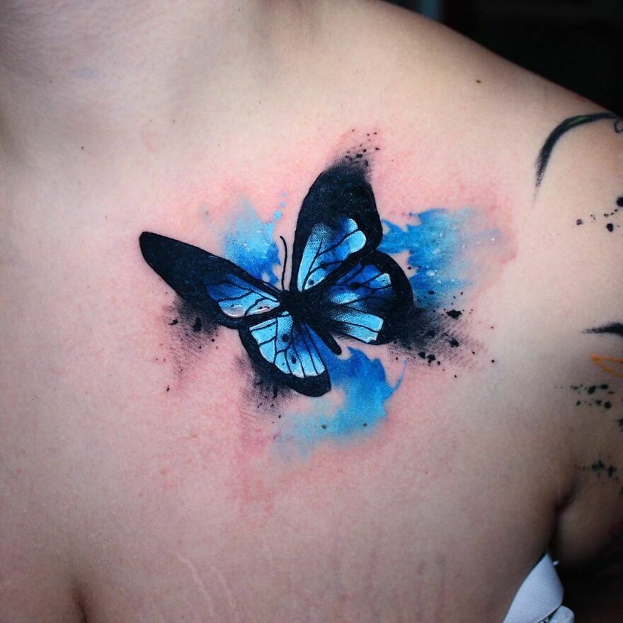 A beautiful watercolor tattoo of a blue butterfly on skin, showcasing artistic design and vibrant colors.