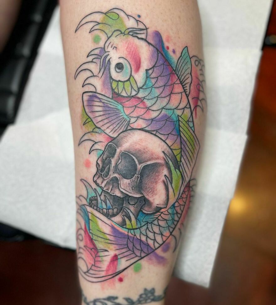 Watercolor tattoo of a colorful koi fish and a skull on an arm, showcasing intricate design and vibrant hues.