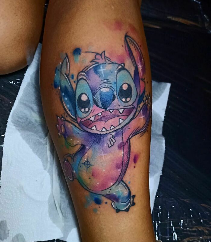 Watercolor tattoo of a cartoon character in vibrant colors on a person's leg.