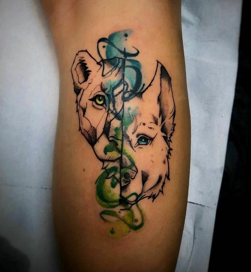 Watercolor tattoo design of a lioness and wolf with vibrant green and blue accents on arm.