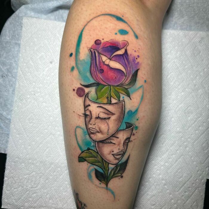 Ethereal watercolor tattoo featuring a purple flower and abstract faces on a person's leg.