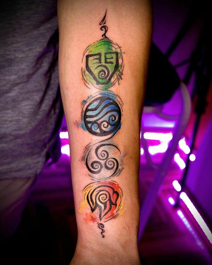 Colorful arm tattoo featuring mystical symbols, showcasing beautiful watercolor design.