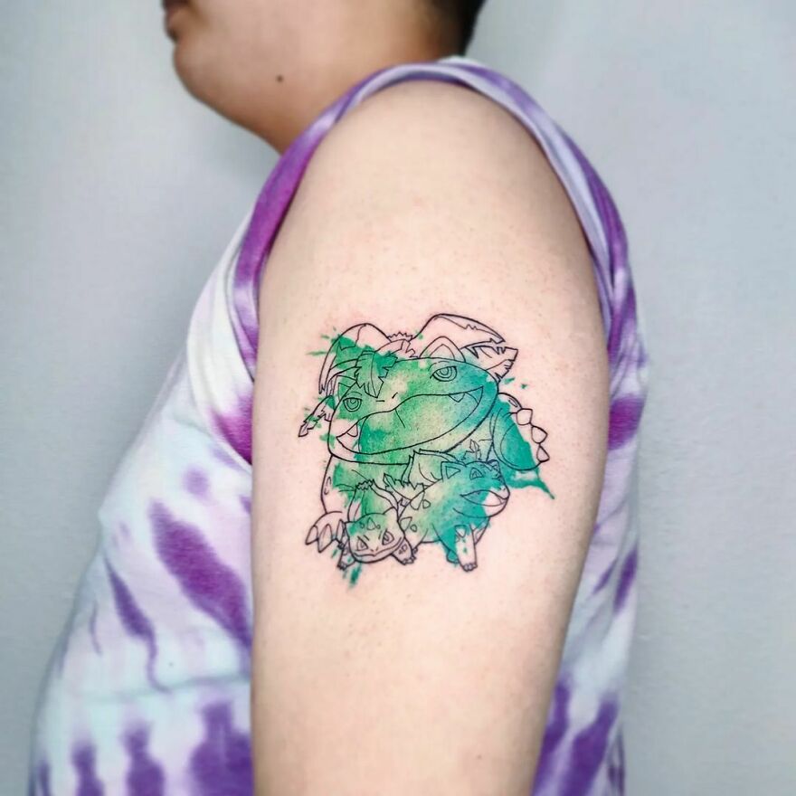 Watercolor tattoo on arm featuring a green and purple design with abstract elements.