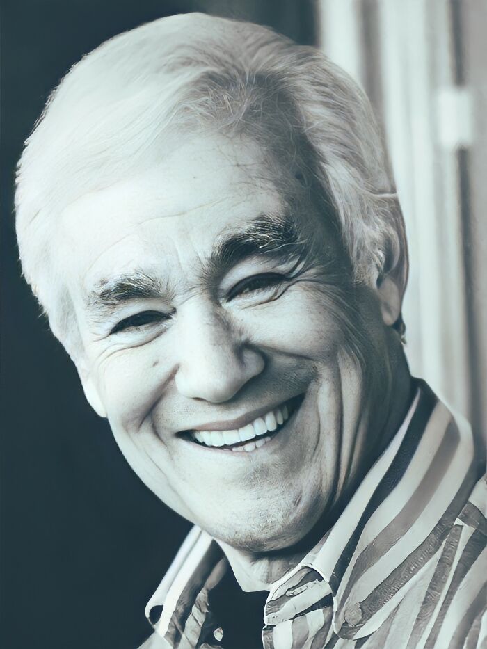 Elderly man with white hair smiling, recreated using artificial intelligence to show how celebrities might look today.