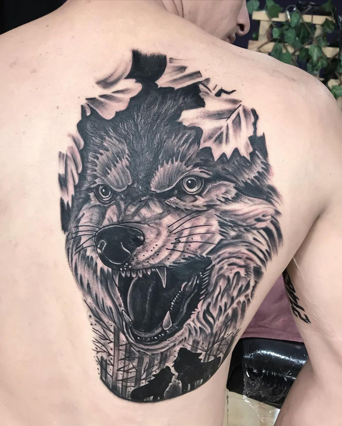 Detailed wolf tattoo on a person's back, showcasing fierce animal artistry.
