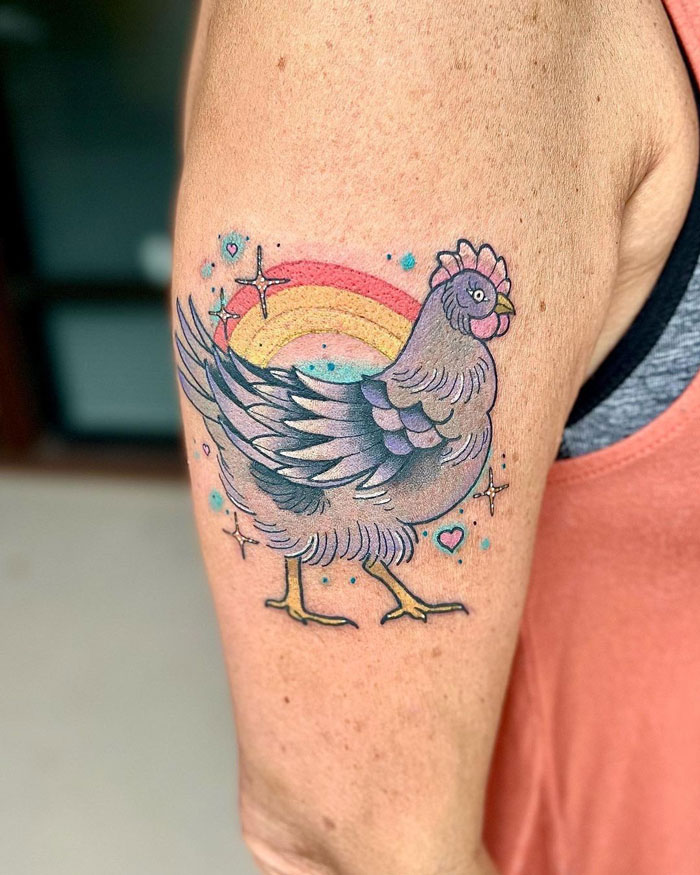 Colorful chicken tattoo on arm with rainbow background, celebrating the animal kingdom.