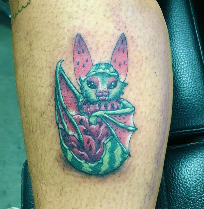 Colorful bat tattoo resembling a watermelon on a person's leg, showcasing creative animal tattoo design ideas.