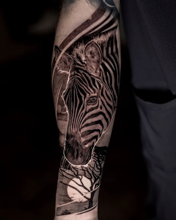 Zebra animal tattoo on arm with intricate black and grey detail, showcasing nature-inspired artistry.