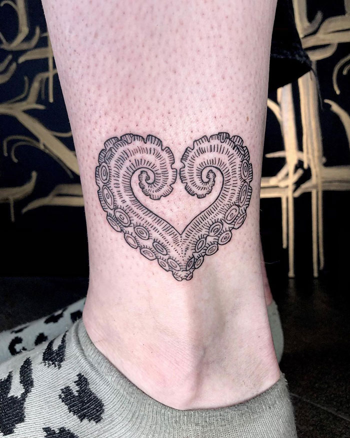 Octopus tentacle tattoo in heart shape on ankle, celebrating the animal kingdom.