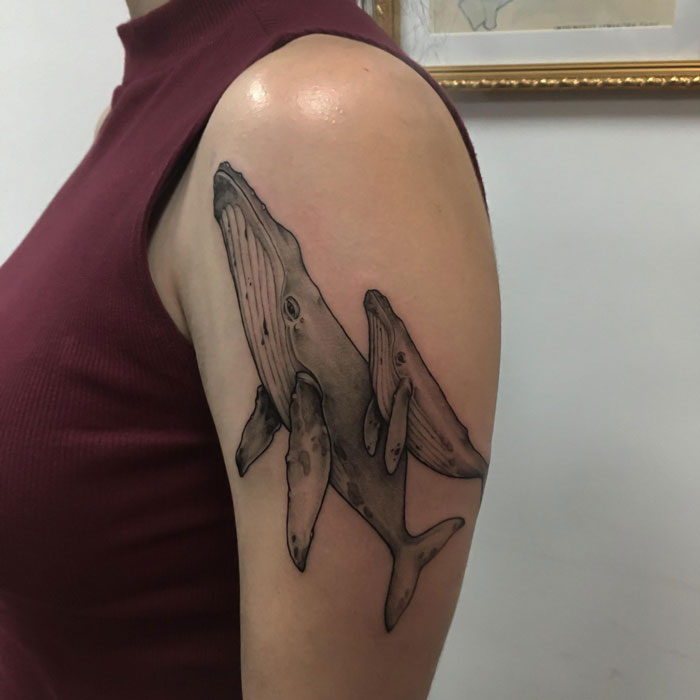 Whale family tattoo on upper arm, showcasing animal tattoo simplicity and realism.