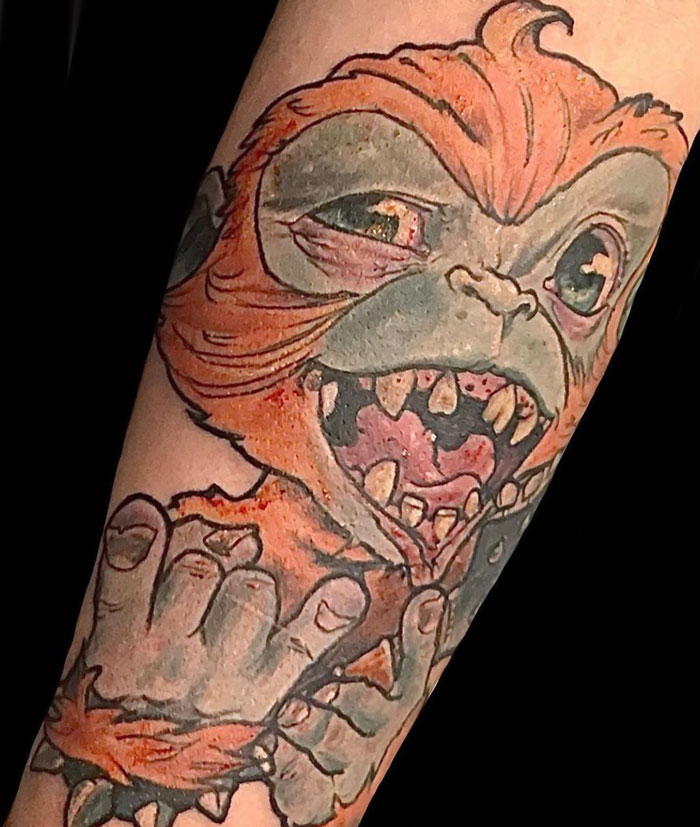 Animal kingdom tattoo of a whimsical creature with orange fur and sharp teeth on a forearm.