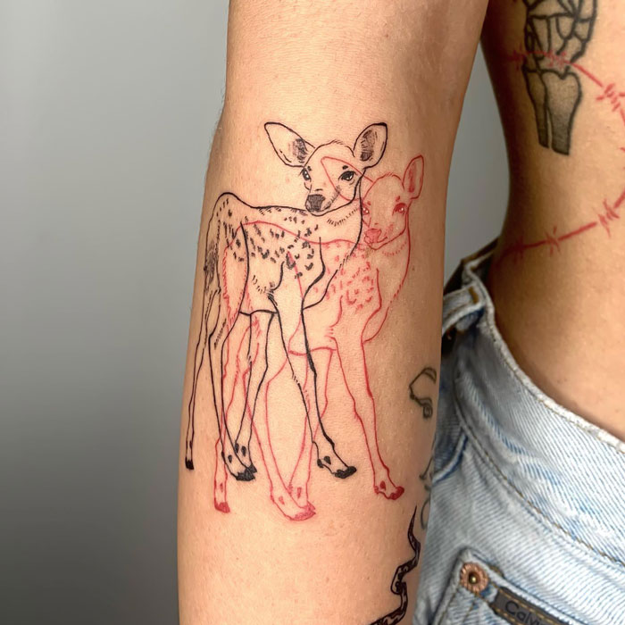 Deer tattoo design on arm featuring two overlapping outlines in red and black ink, showcasing creative animal art.
