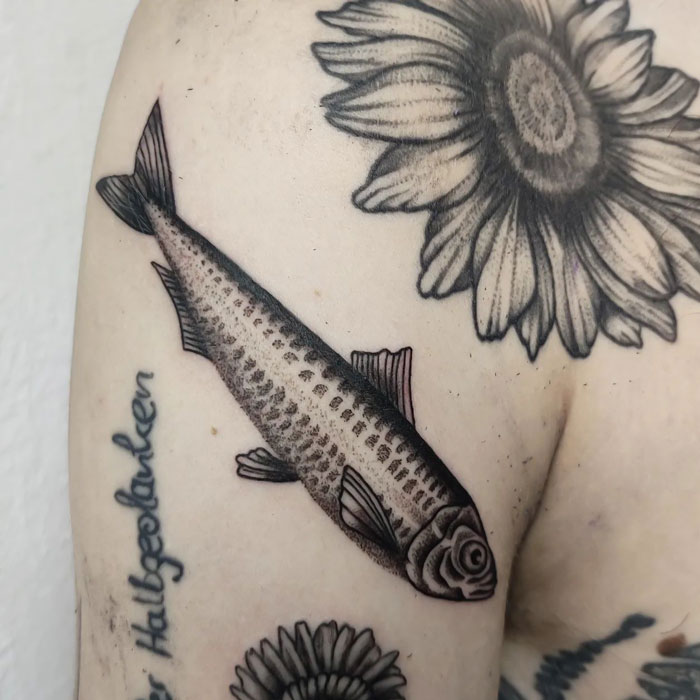 Fish and sunflower tattoos on arm, showcasing creative animal tattoo design.