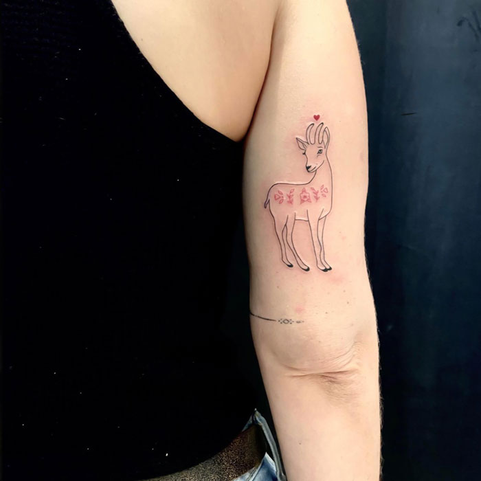 Arm tattoo of a minimalist deer with floral patterns, celebrating the animal kingdom.