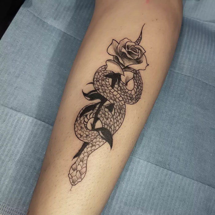 Snake and rose animal tattoo design on forearm.