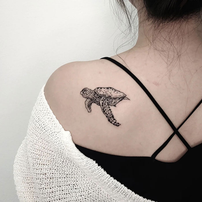 Sea turtle tattoo on shoulder, showcasing intricate animal art.