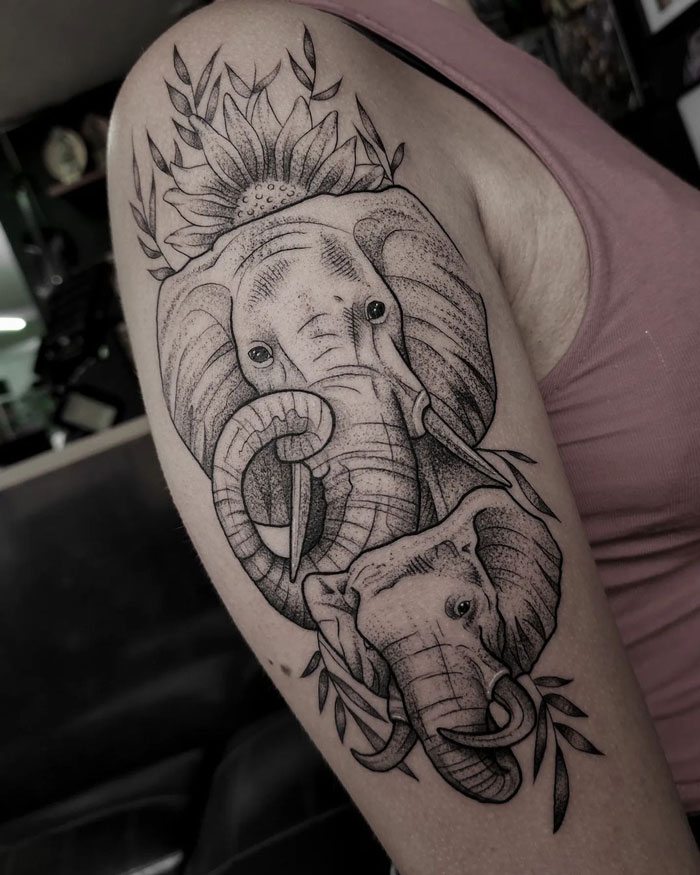 Elephant animal tattoo on arm with sunflower design, showcasing intricate black ink details.