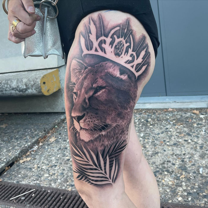 Lion tattoo on a leg, featuring detailed shading, crowned with antlers, celebrating the animal kingdom.