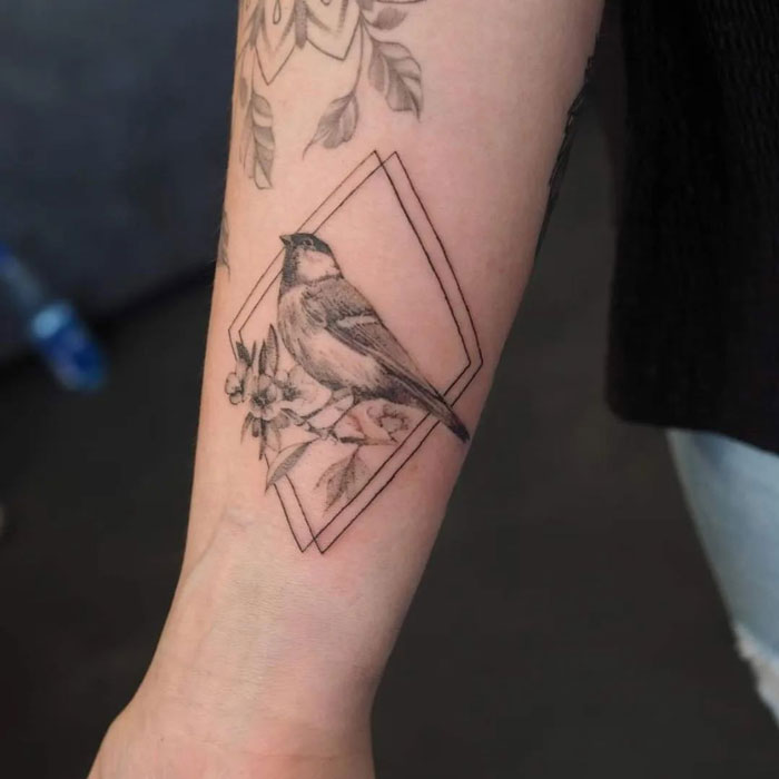 Bird tattoo on forearm with geometric design, showcasing animal kingdom art.