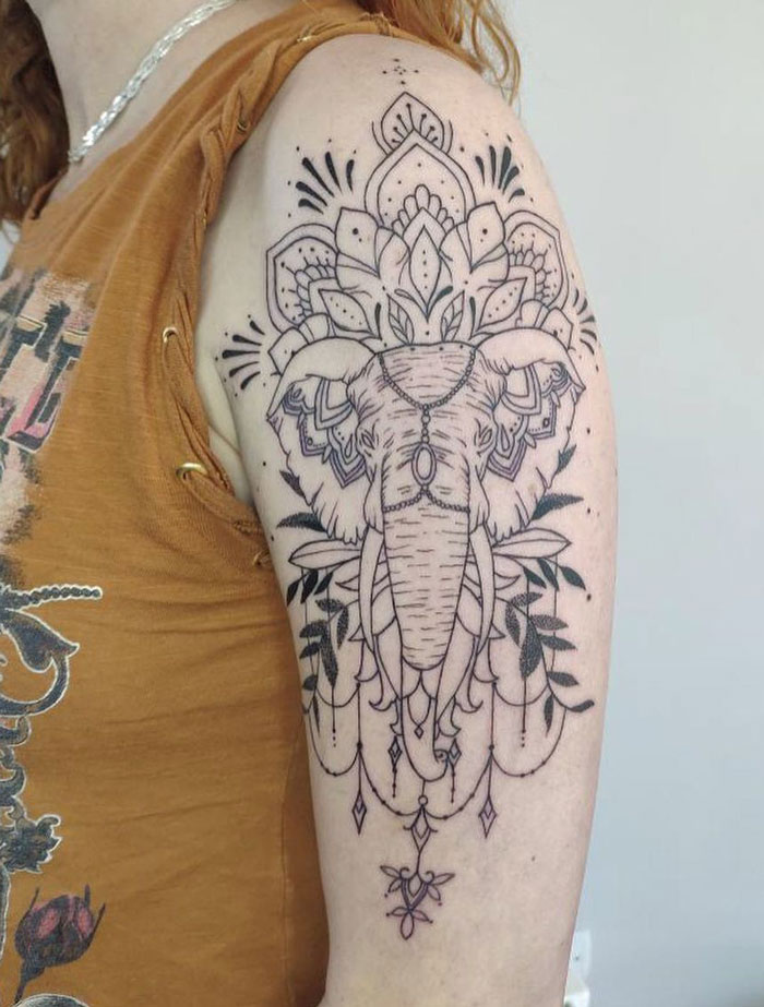 Ornate elephant animal tattoo on a person's upper arm, showcasing intricate line work and mandala patterns.