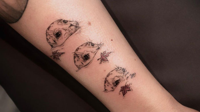 Animal tattoo featuring a simple and realistic otter design with leaves on an arm.