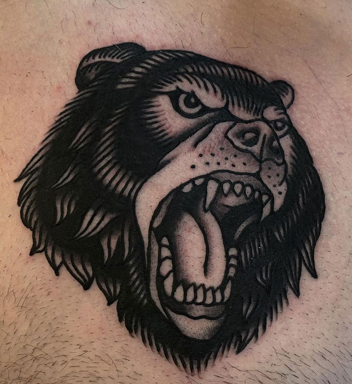 Roaring bear animal tattoo with bold black lines on skin.