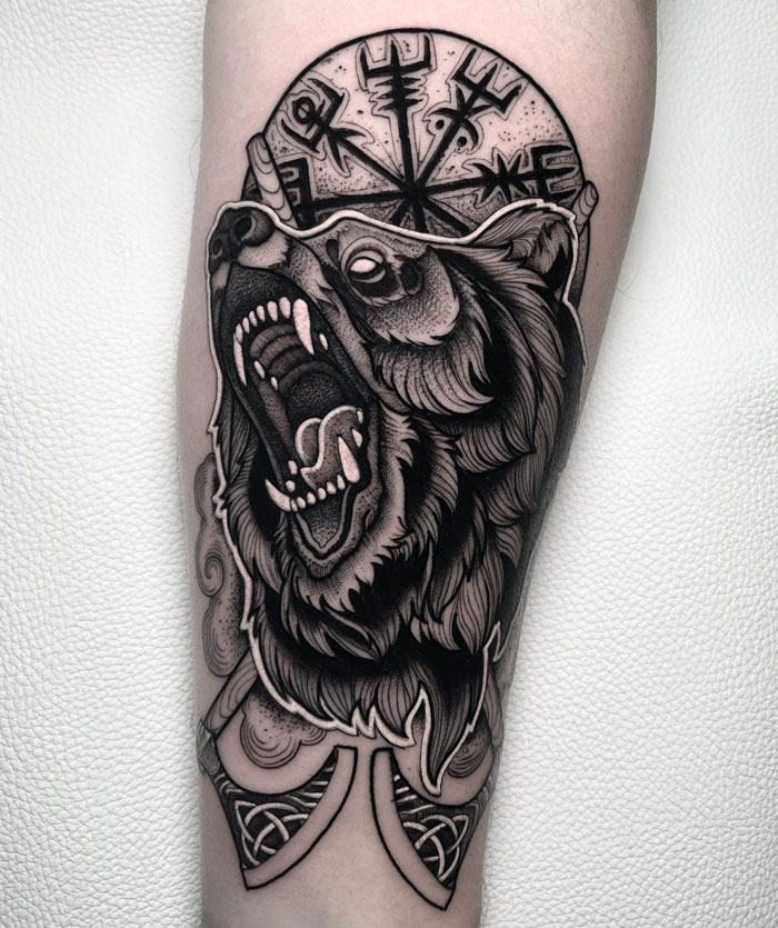 Animal tattoo featuring a roaring bear with mystical symbols, showcasing intricate and bold design elements.