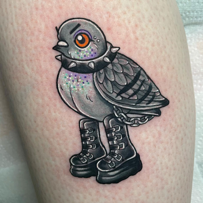 Tattoo of a pigeon wearing a spiked collar and boots, showcasing a whimsical animal tattoo design.