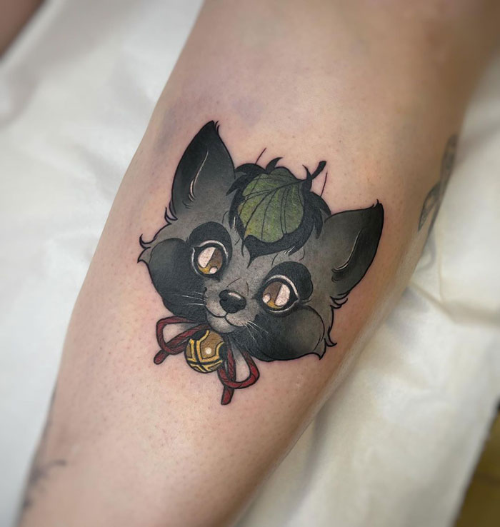 Cute animal tattoo of a cartoon fox with a green leaf on its head, inked on a leg.