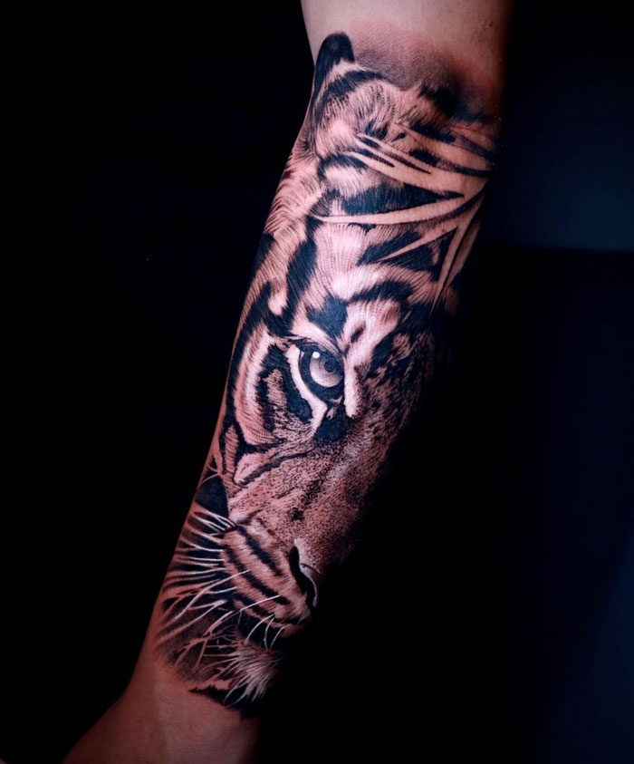 Tiger tattoo on forearm, showcasing detailed animal design with striking features.