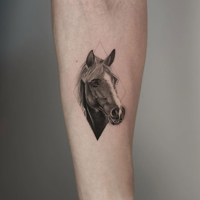 Horse tattoo on arm featuring intricate shading, combining animal art with geometric design for creative inspiration.
