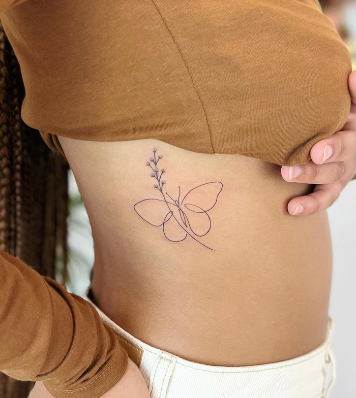 Minimalistic butterfly tattoo on a person's side, illustrating delicate lines celebrating the animal kingdom.