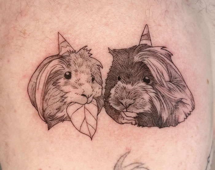 Tattoo of two guinea pigs wearing party hats, celebrating the animal kingdom.