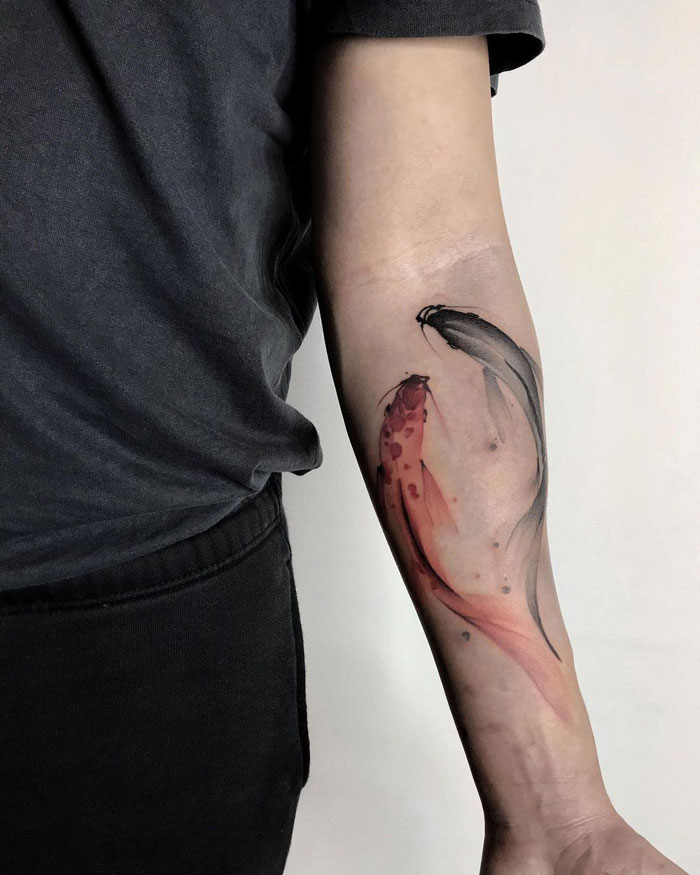 Animal tattoo depicting colorful koi fish on a person's forearm.