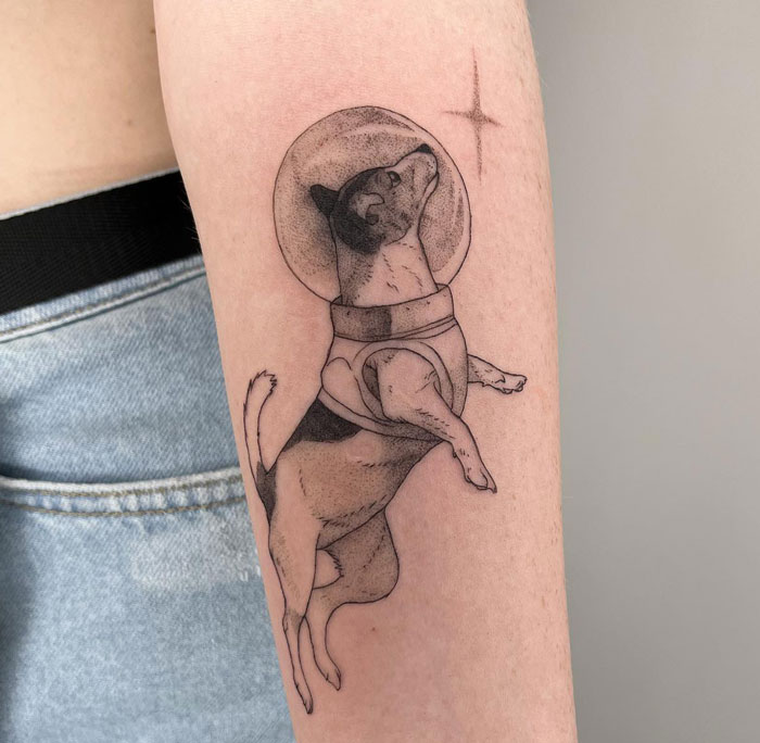 Arm tattoo of a dog in an astronaut suit; creative animal tattoo inspiration.